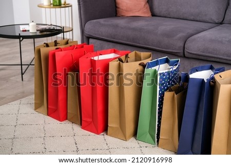 Lots of paper bags after shopping stand at home in the living room by the sofa. seasonal winter and summer sales, shopaholism . online shopping delivery