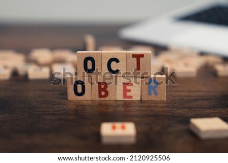 The name of the month October written on wooden cubes od the tabletop of th computer desk. High quality photo