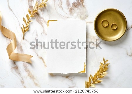 Wedding invitation card mockup, silk ribbon, golden rings and floral branches on marble table. Elegant wedding stationery set Royalty-Free Stock Photo #2120945756
