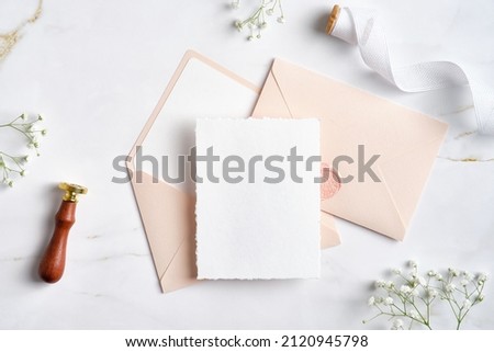Elegant wedding stationery set. Wedding invitation cards template, pastel pink envelopes, silk ribbon, wax seal stamp, flowers on stone table. Flat lay, top view, copy space.