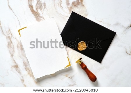 Luxury wedding stationery set. Wedding invitation card mockup, black wedding envelope, wax seal stamp on golden marble desk.