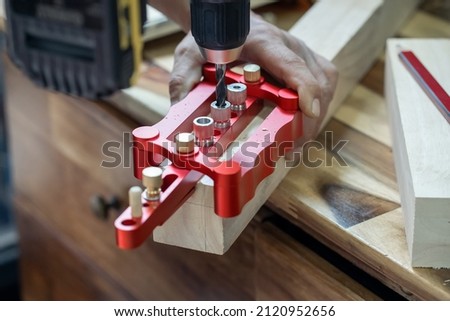 carpenter use drill bit and centering dowel jig tool to make strong joints . woodworking concept.selective focus. Royalty-Free Stock Photo #2120952656