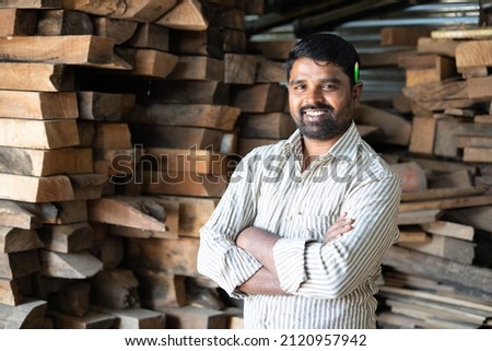 Confident smiling carpenter with arms crossed standing by looking at camera - concept of self confidence, skilled professional occupation and successful worker Royalty-Free Stock Photo #2120957942