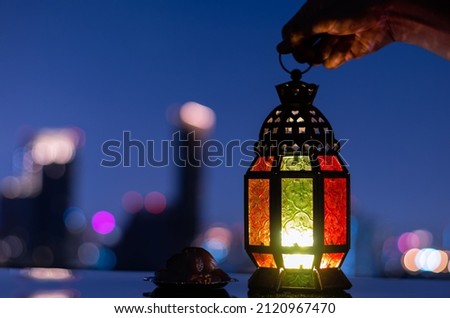 Lantern and small plate of dates fruit with city background for the Muslim feast of the holy month of Ramadan Kareem.