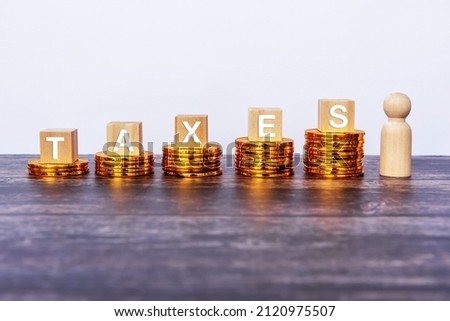 Taxes written on wooden block with stacked coins