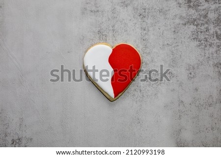 A two tone heart shape sugar cookie with red and white royal icing.