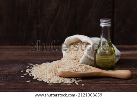Rice bran oil extract with paddy and brown rice on wood table background.  Royalty-Free Stock Photo #2121003659