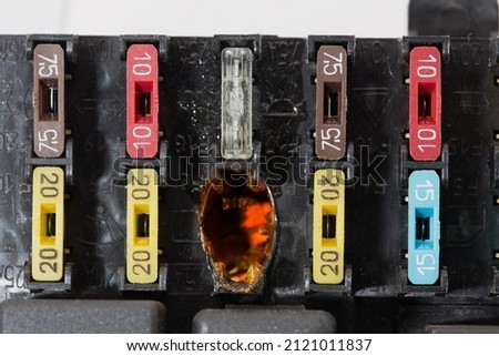 Burnt electrical contacts in the car fuse box. On the body of the unit, the designations of electrical circuits controlled by fuses are applied. Royalty-Free Stock Photo #2121011837