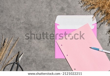 Template or layout with invitation or note, blank sheets of writing paper and purple envelope on gray background decorated with dry grass. Letter in craft envelope, top view of letter envelope and pen