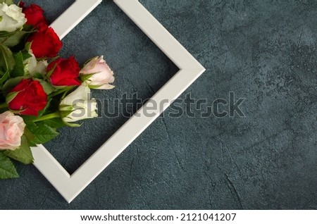 Red and white roses with a photo frame for Valentine's Day, marriage proposal engagement, birthday, anniversary, wedding, Mother's Day. Love composition with copy space on dark background.