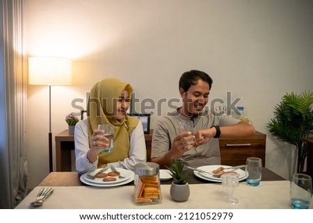muslim couple waiting adhan to break the fast Royalty-Free Stock Photo #2121052979