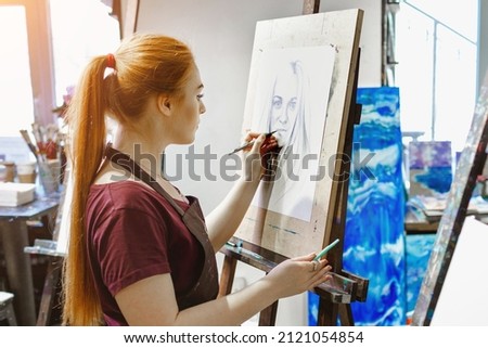 Young girl artist paints a picture in her studio