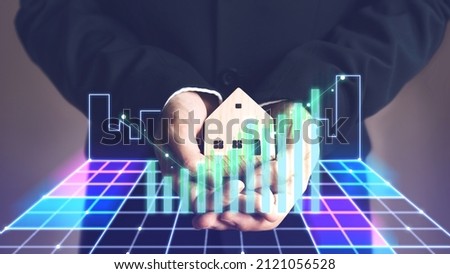 Business leadership man hand holding home model with digital finance growth green graph . Property investment in metaverse cyber concept. 