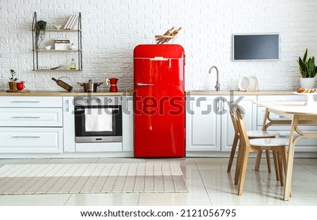 Interior of light kitchen with red fridge, white counters and dining table Royalty-Free Stock Photo #2121056795