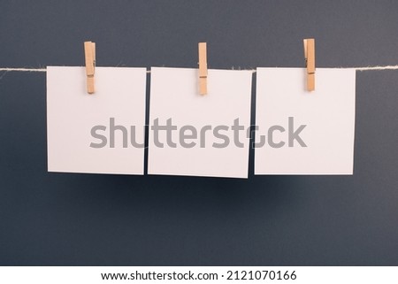 Empty white sheets of paper in a row hanging on a string, copy space for pictures and text, message communication and marketing background, gray color