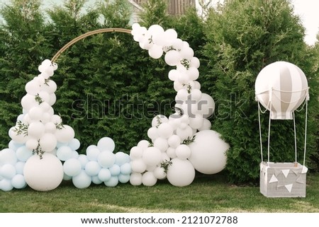 Decorations for holiday party. A lot of balloons blue and white colors. Round photo zone with balls next to a ball with a basket for a child