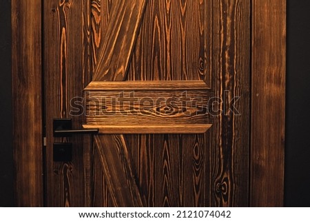 Textured brown door made of natural materials with a black handle. Beautiful eco-friendly door in the interior. Stylish interior design