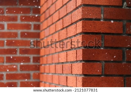 snowflakes falling in front of brick wall