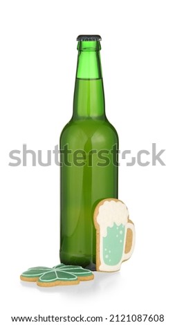 Bottle of beer and gingerbread cookies for St. Patrick's Day celebration on white background