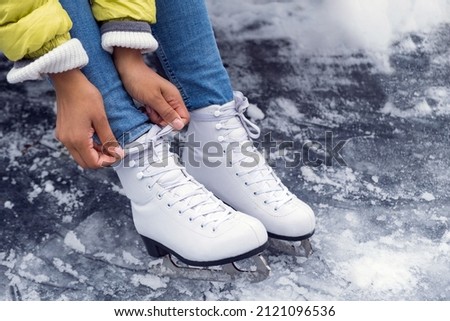 Closeup of African American woman tying shoelaces on ice skates