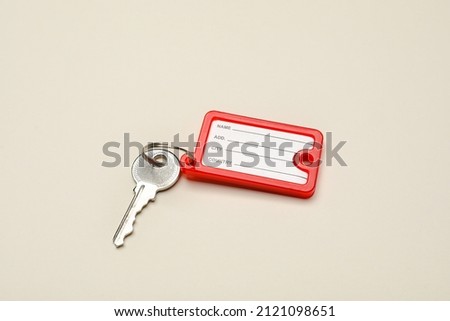 Key with red plastic tag on beige background