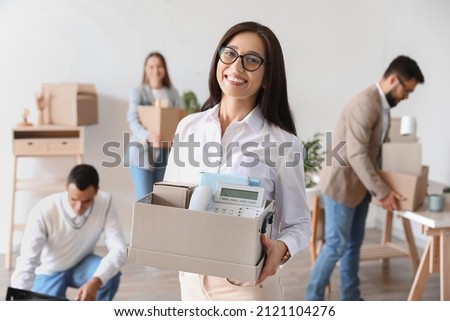 Beautiful woman holding box with personal things in office on moving day