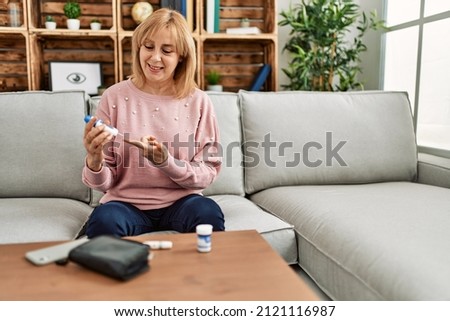 Middle age diabetic woman measuiring glucose using glucometer at home. Royalty-Free Stock Photo #2121116987