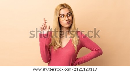 Young Uruguayan blonde woman over isolated background with fingers crossing and wishing the best