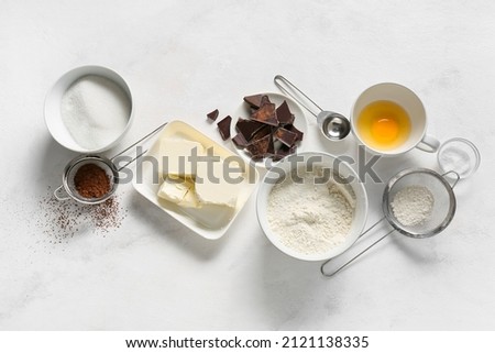 Bowl with butter and ingredients for preparing chocolate brownie on white background Royalty-Free Stock Photo #2121138335