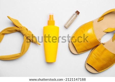 Bottle of sunscreen and beach accessories on white background
