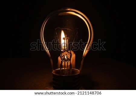 Light bulb with lit candle in background. Blackout city, electricity off, energy crisis or power outage, concept image.  Royalty-Free Stock Photo #2121148706