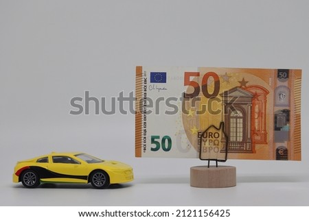 A toy car stands next to a banknote on a stand. Accurate financial calculation when buying a car