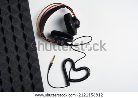 Loving Music, blogging concept background. Headphones with heart shaped cable on white background with copy space and acoustic foam panel, flat lay