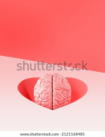 Model of human brain falls into a heart-shaped hole on isolated pastel pink background with orange-red copy space. Surreal minimal abstract concept of falling in love. Valentine’s Day card idea. Royalty-Free Stock Photo #2121168485