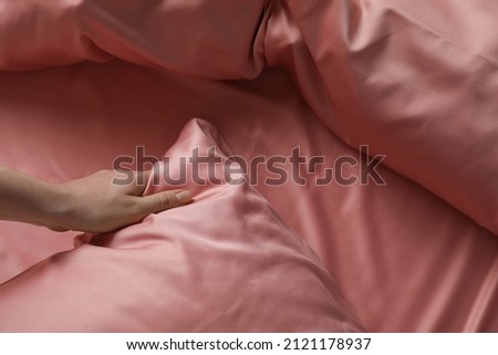 Woman making bed with beautiful pink silk linens, closeup view Royalty-Free Stock Photo #2121178937