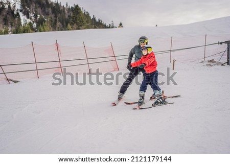 Boy learning to ski, training and listening to his ski instructor on the slope in winter Royalty-Free Stock Photo #2121179144