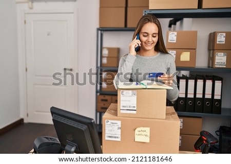 Young blonde woman ecommerce business worker talking on the smartphone holding credit card at office