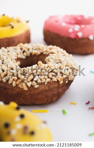 Donuts with nuts, icing and sprinkles on table. Delicious dessert, food background. Closeup, vertical