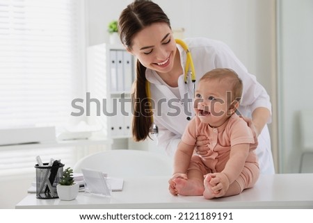 Young pediatrician examining cute little baby in clinic Royalty-Free Stock Photo #2121189191
