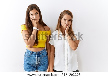 Mother and daughter together standing together over isolated background thinking looking tired and bored with depression problems with crossed arms. 