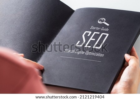 Text " Starter Guide SEO Search Engine Optimization" on page of black book. Royalty-Free Stock Photo #2121219404