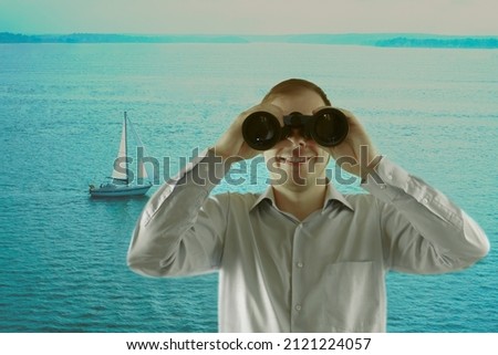 Man wearing shirt with long sleeve and  holding binoculars in hands. He looking at far away and standing on shore. Young business man exploring the ocean. Background of sea and blue water.