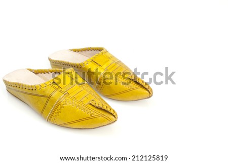 Moroccan girl's handmade yellow slippers. A tiny pair of delicate, intricately detailed yellow slippers from Morocco, isolated on white. Picture from the side, higher up