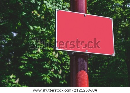 Close-up, Mockup of a red sign on a pole. Against the background of the park
