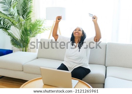 A Photo of pretty black woman using laptop at home sofa and buy something on the web