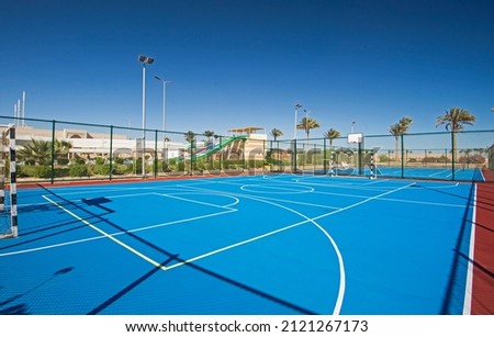 Outdoor clay multi purpose sports pitch with blue surface and nets at tropical hotel holiday resort Royalty-Free Stock Photo #2121267173