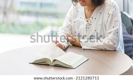 Woman sitting near the window reading a book 