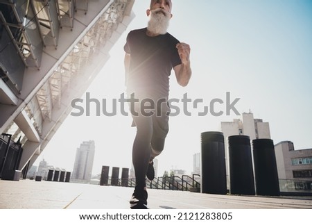 Photo of confident mature coach man run forward accept marathon challenge wear t-shirt urban town outdoors