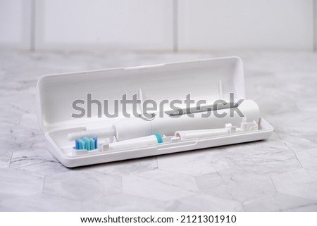 Modern white sonic or electric toothbrush in travel case. Concept of professional oral care and healthy teeth by using sonic smart toothbrush. Minimal design