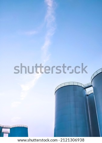 Low angle view of storage fuel tanks inside of petroleum industrial area against blue sky in evening time